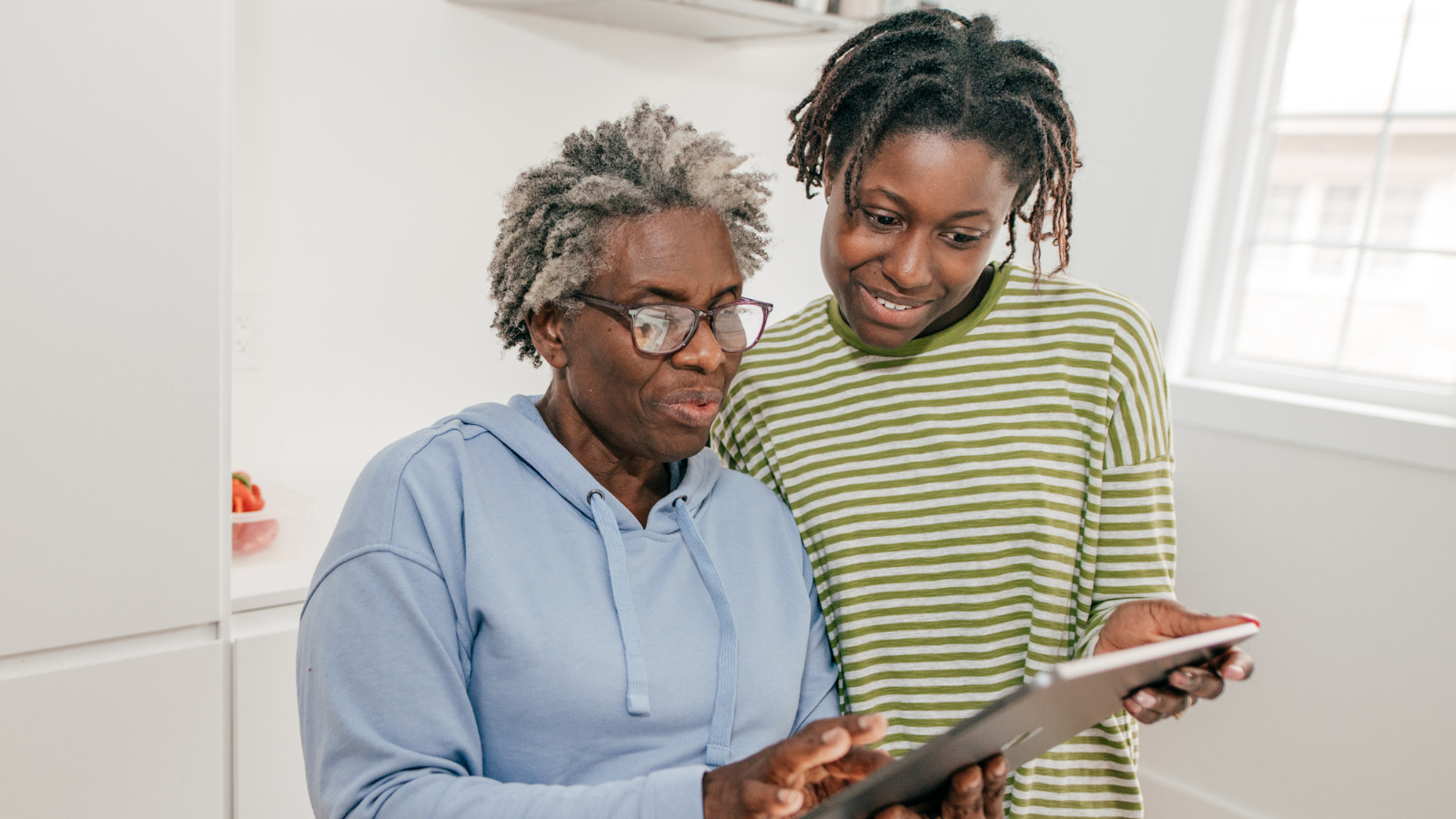 two women standing with an tablet