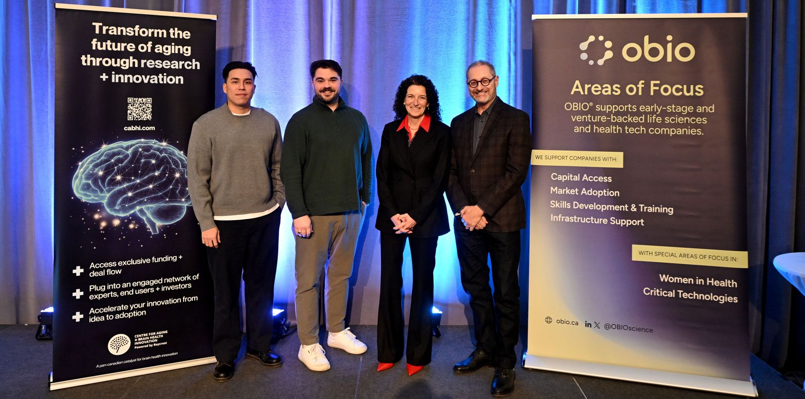 Four people standing on a backlit stage